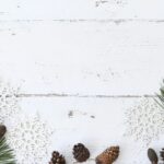 Simple holiday arrangement with snowflakes and pine cones on a white wooden background.